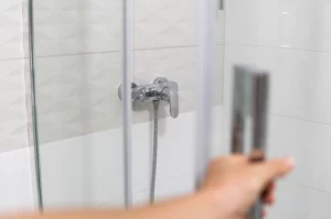 Une personne ouvrant une porte de douche